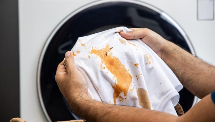 Foto de camisa manchada com uma máquina de lavar de fundo