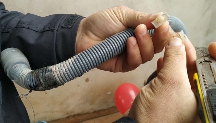 Homem segunrando a mangueira de uma máquina de lavar