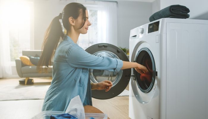 Mulher colocando roupas em uma máquina de lavar frontal