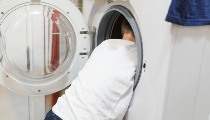 Homem tirando roupas de uma máquina de lavar