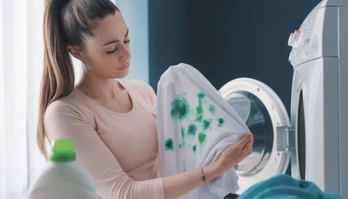 Foto de uma mulher segurando uma blusa branca com manchas